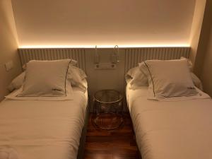 two beds sitting next to each other in a room at Yuhom casas con alma Galera 4º in A Coruña