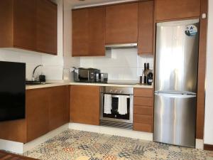 a kitchen with wooden cabinets and a stainless steel refrigerator at Yuhom casas con alma Galera 4º in A Coruña