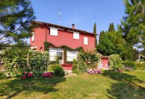 une maison rouge avec des fleurs dans la cour dans l'établissement B&B Le Stagioni, à Loreto Aprutino