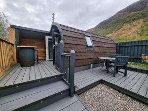 a wooden deck with a table and a building at Riverside Pod, West Highland Way Holidays in Kinlochleven