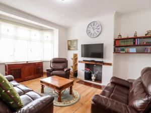 sala de estar con muebles de cuero y reloj en la pared en Ninety Eight, en Southend-on-Sea