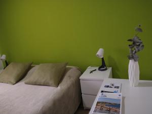 a green bedroom with a bed and a table with a lamp at PENSION132 in A Coruña