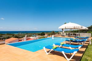 Cette villa dispose d'une piscine avec des chaises et un parasol. dans l'établissement Villa Magdalena, à Alaior