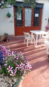 um pátio com uma mesa, cadeiras e flores em Dhalia Appartamenti Trapani em Trapani