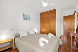 1 dormitorio con 1 cama con 2 toallas en Tramontana Apartment 99BJ, en Fornells