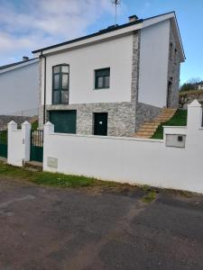a house with a white wall and a fence at Sleeping portomarin 1 in Portomarin