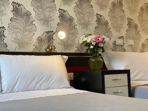 Un dormitorio con una cama con un jarrón de flores en Hotel RossoVino Milano, en Milán