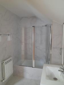 baño blanco con ducha y lavamanos en Sleeping portomarin 1 en Portomarin