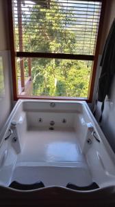 uma banheira branca na casa de banho com uma janela em Casa de Montanha na Praia em Ilhabela