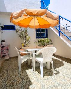 einen Tisch und Stühle mit Sonnenschirm auf einer Terrasse in der Unterkunft Maison de la Lagune in Oualidia