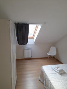 um quarto com uma janela, uma cama e uma cadeira em Sleeping portomarin 1 em Portomarin