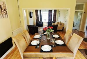 - une table à manger avec des assiettes et des fleurs dans l'établissement Fairview Cottage Watford, à Leavesden Green