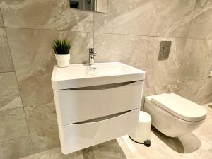 a bathroom with a white sink and a toilet at Stunning & Stylish 2 Bedroom Apartment! - 5 Minute Walk to the Best Beach! - Great Location - FREE Parking - Fast WiFi - Smart TV - Newly decorated - sleeps up to 4! Close to Bournemouth & Poole Town Centre & Sandbanks in Bournemouth