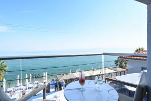 a table with wine glasses on a balcony with the ocean at Emily's Luxury Suites in Pefkochori