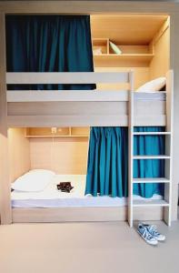 two bunk beds in a room with blue curtains at L'Etape du Mont, Family Hostel in Pontorson