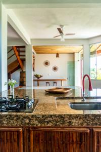 an open kitchen with granite counter tops and a ceiling fan at Bahia Soul - Casa Mar - Grupo Barril Hospedagens in Taipu