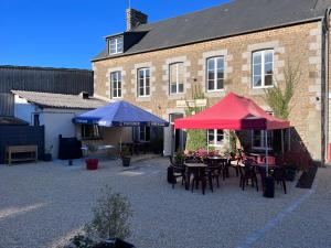 un patio avec des tables et des parasols en face d'un bâtiment dans l'établissement Au Père Tranquille, à Tinchebray