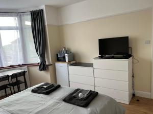 a bedroom with a bed and a tv on a dresser at North West Lodge Guest House in London