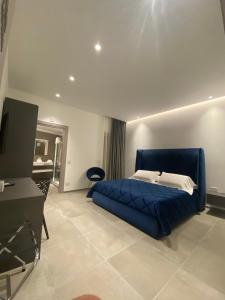 a bedroom with a blue bed and a television at IL DUCA HOUSE e HOLIDAY PRESTIGE in Caccamo