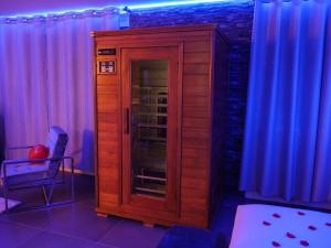 a wooden cabinet with a glass door in a room with curtains at Appartement - Jacuzzi - Pour deux in Besançon