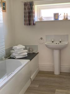 La salle de bains blanche est pourvue d'un lavabo et d'une baignoire. dans l'établissement Bramble cottage at Waingrove Farm, à Louth