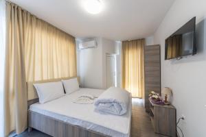 1 dormitorio con 1 cama con sábanas blancas y TV en Мотел "Релакс" Motel "Relax", Балчик,, en Balchik