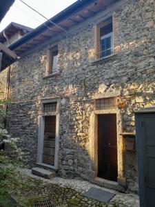 an old stone house with two doors in front of it at Antica Calvasino in Lezzeno