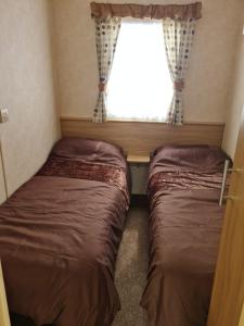 two beds in a small room with a window at Superb 8 Berth Caravan, Golden Anchor Park in Chapel Saint Leonards