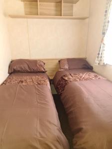 two beds are in a small room withermottermott at Superb 8 Berth Caravan, Golden Anchor Park in Chapel Saint Leonards