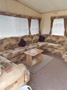 チャペル・セント・レオナルズにあるSuperb 8 Berth Caravan, Golden Anchor Parkのソファとテーブルのあるリビングルーム