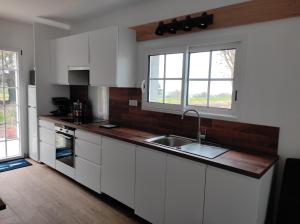 a kitchen with white cabinets and a sink and two windows at Ty gwenn in Cancale