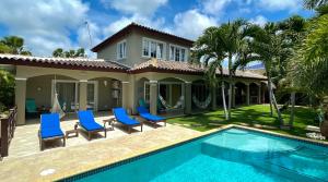 a villa with a swimming pool and blue chairs at Hibiscus Beach House in Willemstad