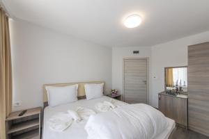 a bedroom with a white bed with white sheets at Мотел "Релакс" Motel "Relax", Балчик, in Balchik
