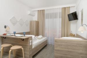 a hotel room with a tub and a bed and two chairs at SAND rooms to let in Nea Roda