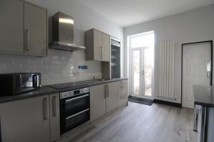 a kitchen with white cabinets and a stove top oven at Anfield house in Liverpool