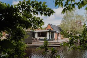 una casa en el agua con un muelle en B&B Oan't Wetter, en Dokkum