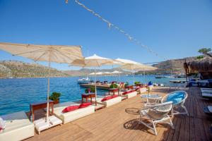 a wooden deck with chairs and umbrellas on the water at Baldan Suites in Bozburun