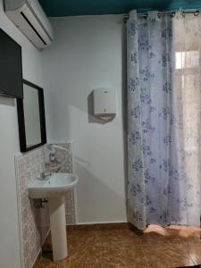 baño con lavabo y cortina de ducha en M-A Catrachos Rooms, en Madrid