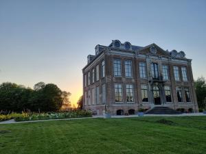 a large brick building with a lawn in front of it at B&B Huis der Boede in Koudekerke