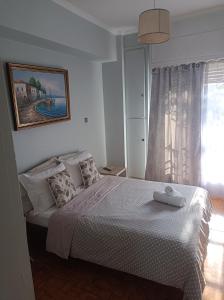 a bedroom with a bed with a white bedspread and a window at Historic Center Apartment at Thisseio in Athens