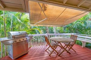 een grill en een tafel en stoelen op een veranda bij Waimea Bay Garden Bunglaow in Haleiwa