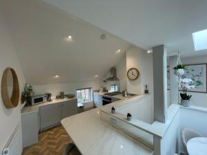 a large kitchen with white counters and a clock on the wall at Lees Lookout Holt ,2 bedroom luxury apartment with private parking in Holt