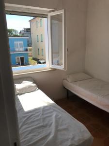 Cette petite chambre comprend 2 lits et une fenêtre. dans l'établissement VIRGOLA ZERO HOLIDAY BEACH, à Porto Potenza Picena