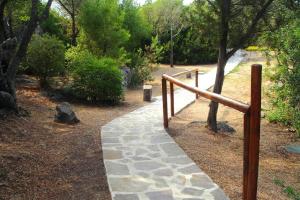 un camino de piedra en un parque con barandilla de madera en Holiday residence Sa Jaga Brujada in Porto Rotondo, en Porto Rotondo