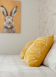 a bed with two pillows and a picture of a rabbit at Thisledo Holiday Cottage, Woodman Terrace, Skipton - Pet Friendly in Skipton