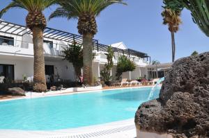 a swimming pool in front of a house with palm trees at Los Tulipanes in Puerto del Carmen