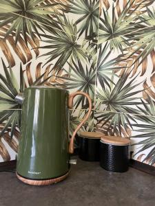 zielony czajnik do herbaty siedzący na stole przed ścianą w obiekcie Domek Zielony w Unieściu