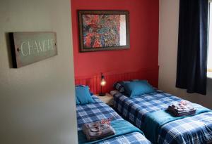 two beds in a room with red walls at Le Balcon Bleu, gîte located in Millevaches National Park in Chavanac