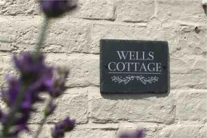 a sign on a brick wall with purple flowers at Wells Cottage in Malvern Wells