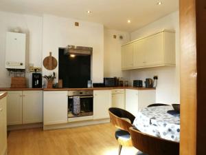 a kitchen with white cabinets and a table with chairs at Wells Cottage in Malvern Wells